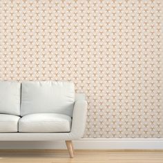 a white couch sitting in front of a wall with an intricate pattern on the wall