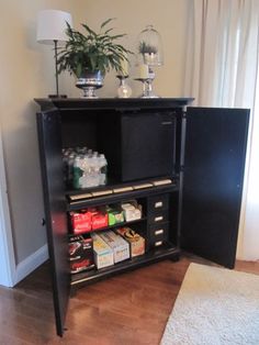 a black cabinet with drinks and snacks in it next to a white rug on the floor