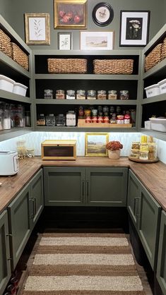 a kitchen with green cabinets and shelves filled with food on top of wooden counter tops