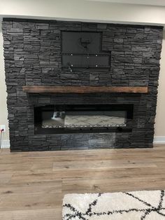 a living room with a stone fireplace and wood flooring on the wooden floor, along with a white rug