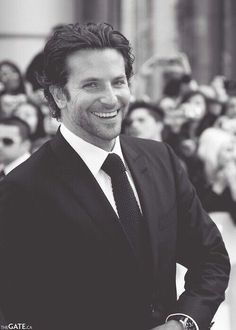 a man in a suit and tie smiles for the camera while people look on from behind him