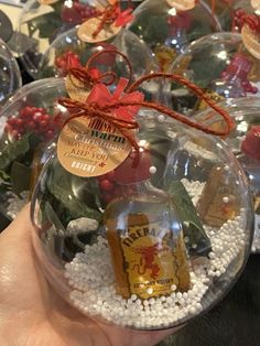 a hand holding a glass ornament filled with christmas decorations and wine bottles in it