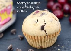 a close up of a muffin on a table with cherries in the background