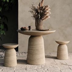 an outdoor table with two stools next to it and a potted plant on top