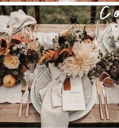 the table is set with plates, silverware and orange flowers on top of them