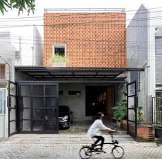 a person riding a bike in front of a house with an open door and brick roof