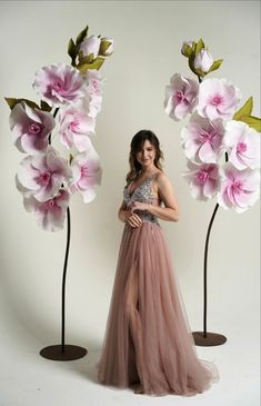 a woman standing in front of two tall flowers