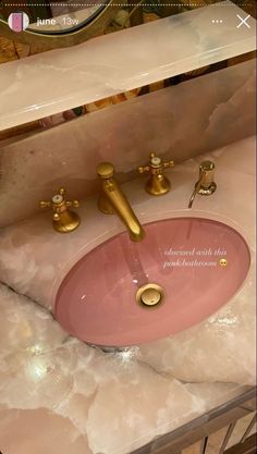 a bathroom sink with gold faucets and pink basin