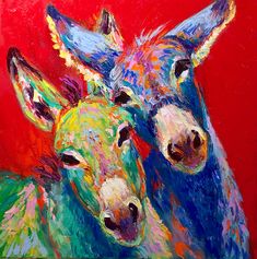 two colorfully painted donkeys standing next to each other in front of a red background