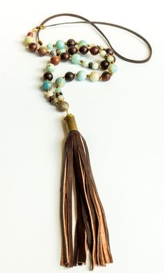 Amazonite, gold hematite, wood beads and brown leather cord with micro pave' bead and repurposed brown lambskin bullet shell tassel. Necklace is approximately 35". Looks great with our Amazonite Tibetan Agate Bracelet Set which is sold separately. All of our tassels are handmade from leather remnants sourced from upholstery and garment factories. Every item sold plants a tree through our partnership with One Tree Planted. Pyrite Bracelet, Bullet Shell, Pave Beads, Hematite Bracelet, Gemstone Beaded Bracelets, Agate Bracelet, Trendy Necklaces, Shell Jewelry, Gemstone Bracelets