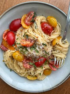 a white bowl filled with pasta, tomatoes and parmesan cheese