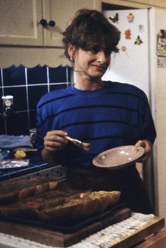 a woman holding a plate with food on it in front of a stove top oven