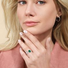 a woman with blonde hair and blue eyes wearing a pink shirt holding her hand to her face