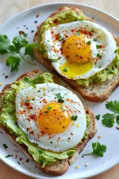 two eggs on toast with avocado and cilantro sprinkled on top