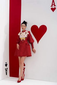 a woman standing in front of a red and white wall with a heart on it