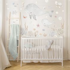 a baby's room with a white crib and wall decals on the walls