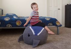 a young boy sitting on top of an elephant shaped bed in a room with a blue bedspread