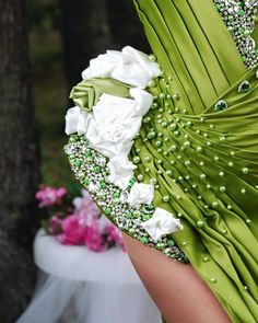 a woman wearing a green dress with white flowers on the waist and in the back