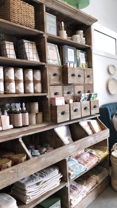 an old wooden shelf filled with lots of crafting supplies and storage bins next to a blue couch