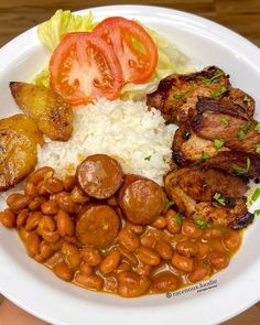 a white plate topped with meat, beans and rice