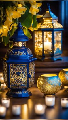 blue lanterns with yellow flowers and lit candles are on the table next to each other