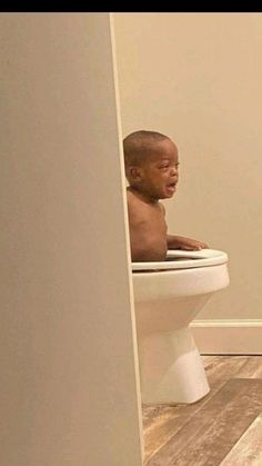 a man sitting on top of a toilet in a bathroom