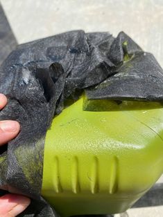 a person is holding a green object in their left hand and it's covered with black material