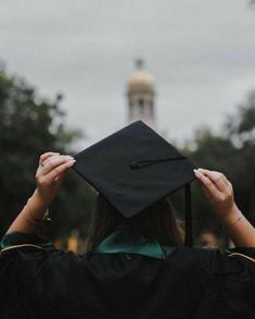 a person wearing a graduation cap and gown holds their hands up to the side as they stand in front of a building