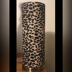 a black and white leopard print vase sitting on top of a wooden table next to a wall