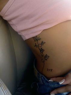 a woman's stomach with a small flower tattoo on the side of her belly