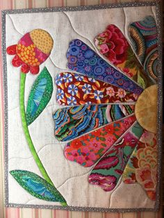 a quilted wall hanging with colorful flowers on it