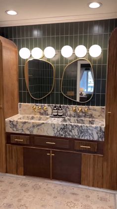 a bathroom with marble counter tops and two mirrors on the wall, along with wooden cabinets