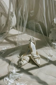 a pair of white shoes sitting on top of a bed covered in plastic sheets and flowers