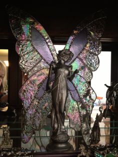 a glass sculpture of a fairy holding a butterfly on top of a table in front of a window