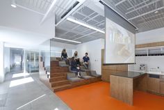 three people are sitting on the stairs in an office with orange flooring and white walls