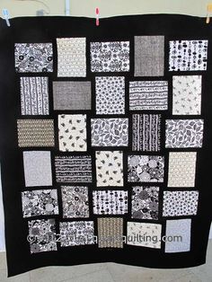 a black and white quilt hanging on a wall