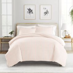 a bed with pink and white striped comforter in a room next to two windows