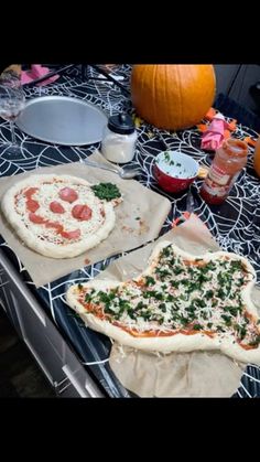 two pizzas sitting on top of baking sheets next to pumpkins and other food