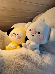 two stuffed animals sitting on top of a bed