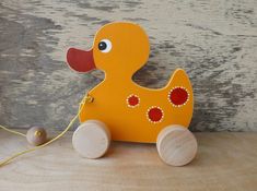 an orange wooden toy duck with red eyes