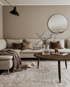 a living room filled with furniture and a round mirror on the wall above it's coffee table