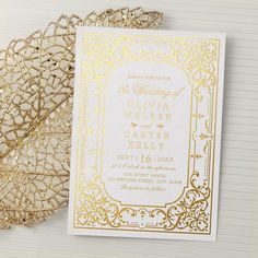 the wedding stationery is gold and white with an intricate design on it, along with a lace doily