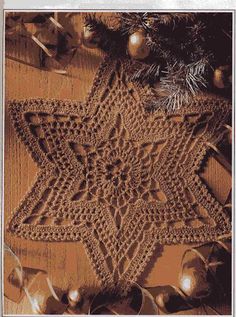 a crocheted star is sitting on the floor next to christmas ornaments and pine cones