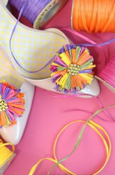 several different types of colorful thread and spools on a pink surface with white shoes