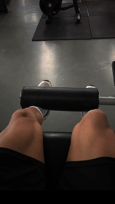 the legs of a person who is sitting on a bench with a barbell in front of them