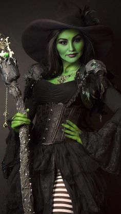 a woman dressed in green and black holding a wand