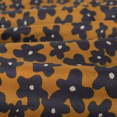 an orange and black flower print fabric with white polka dots on the bottom half of it