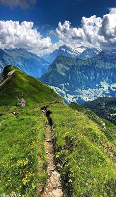 a path leading to the top of a mountain with mountains in the background and clouds overhead