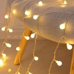 a chair covered in white lights on top of a wooden legrest with string lights strung across the seat