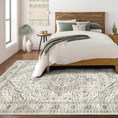 a large bed sitting on top of a wooden floor next to a white and green rug